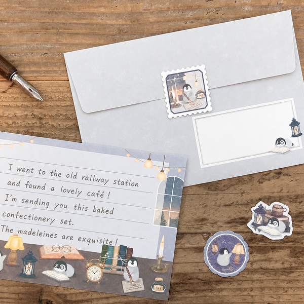 Stationery items including an envelope, postcard, and stickers on a wooden surface.