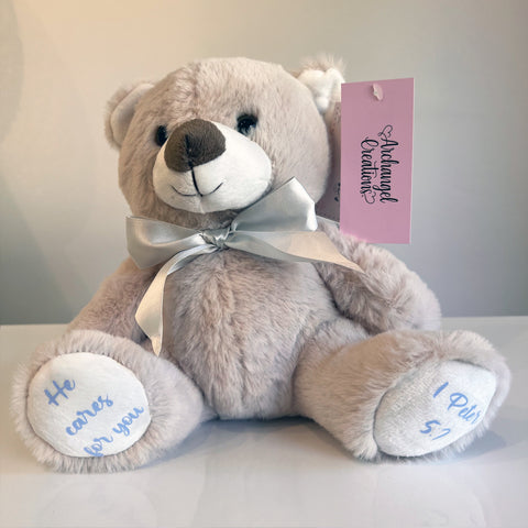 Plush teddy bear with a silver bow, He cares for you Bible verse