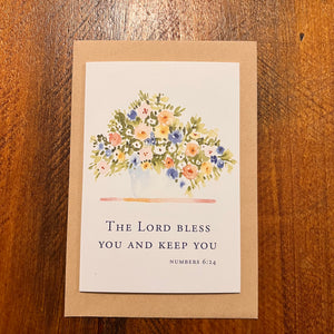 Greeting card with floral design and Bible verse on a wooden surface