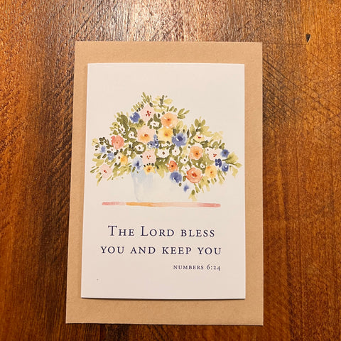 Greeting card with floral design and Bible verse on a wooden surface