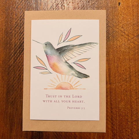 Card with a hummingbird illustration and Proverbs 3:5 quote on a wooden surface