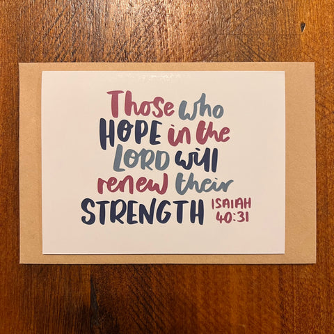 Card with motivational quote 'Those who hope in the Lord will renew their strength' from Isaiah 40:31 on a wooden surface.