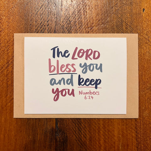 Card with 'The Lord bless you and keep you' text on a wooden surface