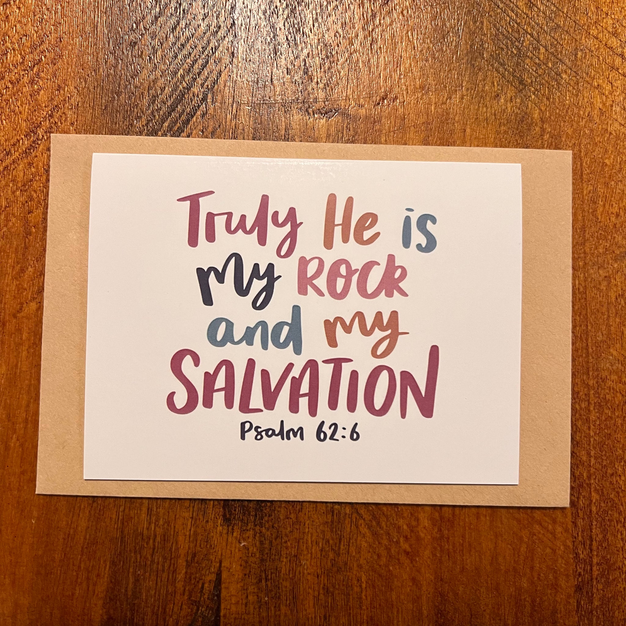 Card with 'Truly He is My Rock and My Salvation' text on a wooden surface