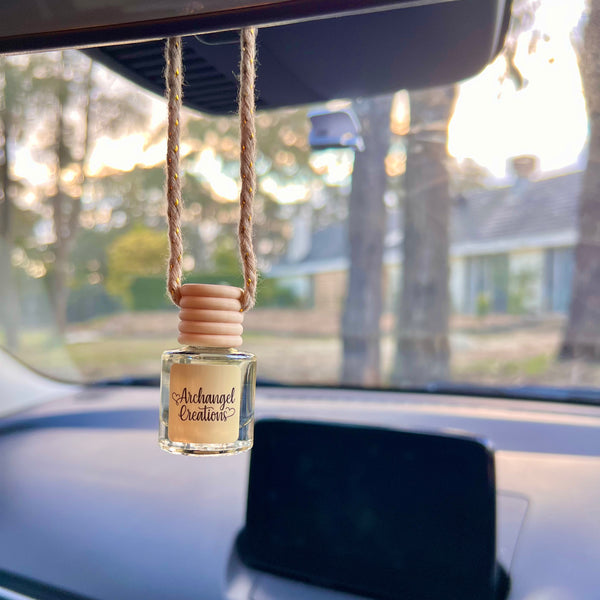 Car air freshener hanging from a rearview mirror with a blurred outdoor background