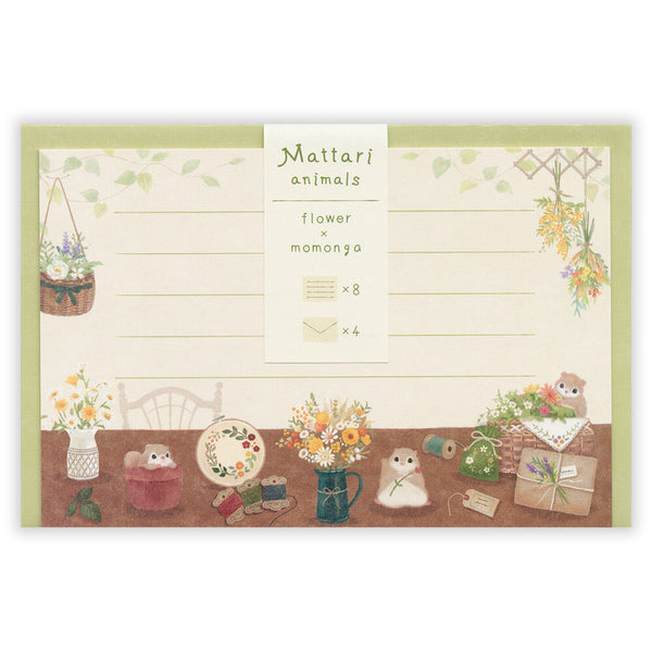 A flat-lay view of a stationery set featuring a 'Mattari animals flower momongo' notepad. The cream-colored notepad has lined writing space, a central label, and a decorated bottom border with cute illustrations of small animals, flowers, and gifts.