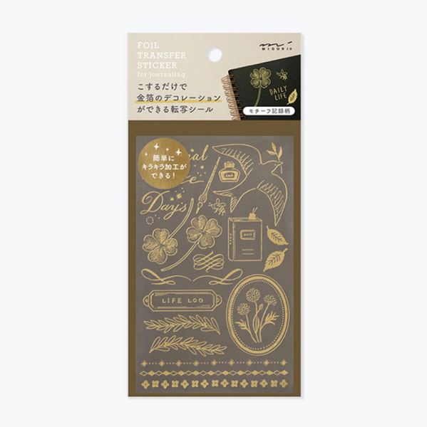 A package of gold foil transfer stickers for journaling, featuring various elegant designs like a bird, flowers, leaves, and decorative borders on a dark brown backing sheet.