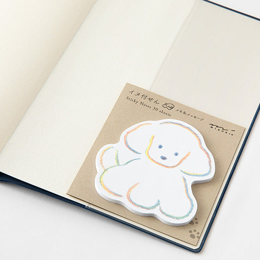 Notebook with a dog-shaped sticky note on a plain background