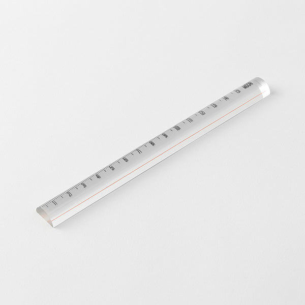 A clear acrylic ruler with black printed measurement markings and a thin orange accent line, shown diagonally on a light gray background.